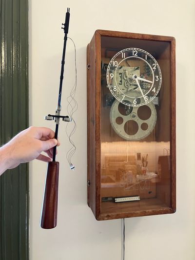Pendulum being held next to the clock, with compensator halfway up.