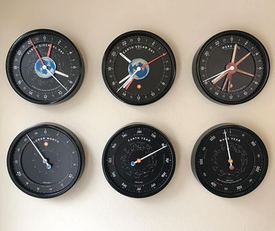 A row of wall clocks keeping solar, sidereal, lunar and Martian time.