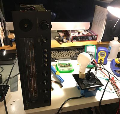 Stereo on its side, plugged into a junction box with a switch and a bulb in the socket.
