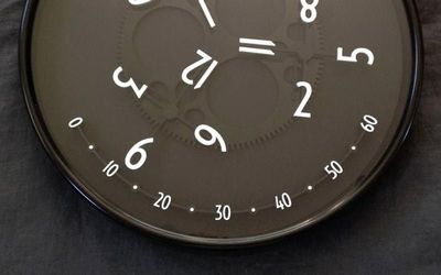 A wandering hour clock, its hour numeral travelling across a minute arc.