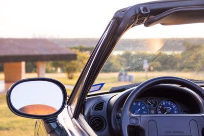 Wide shot from outside the car, showing partial view through the windshield, and a glimpse of the gauges behind the steering wheel.