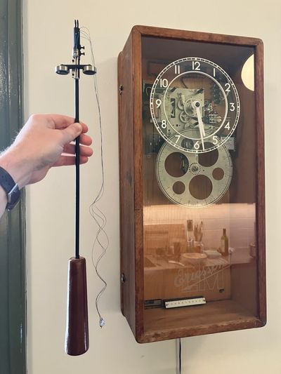 Pendulum being held next to the clock, with compensator near top.